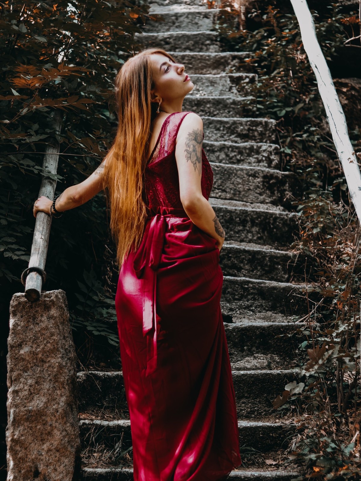byliv in a red satin gown on stone steps